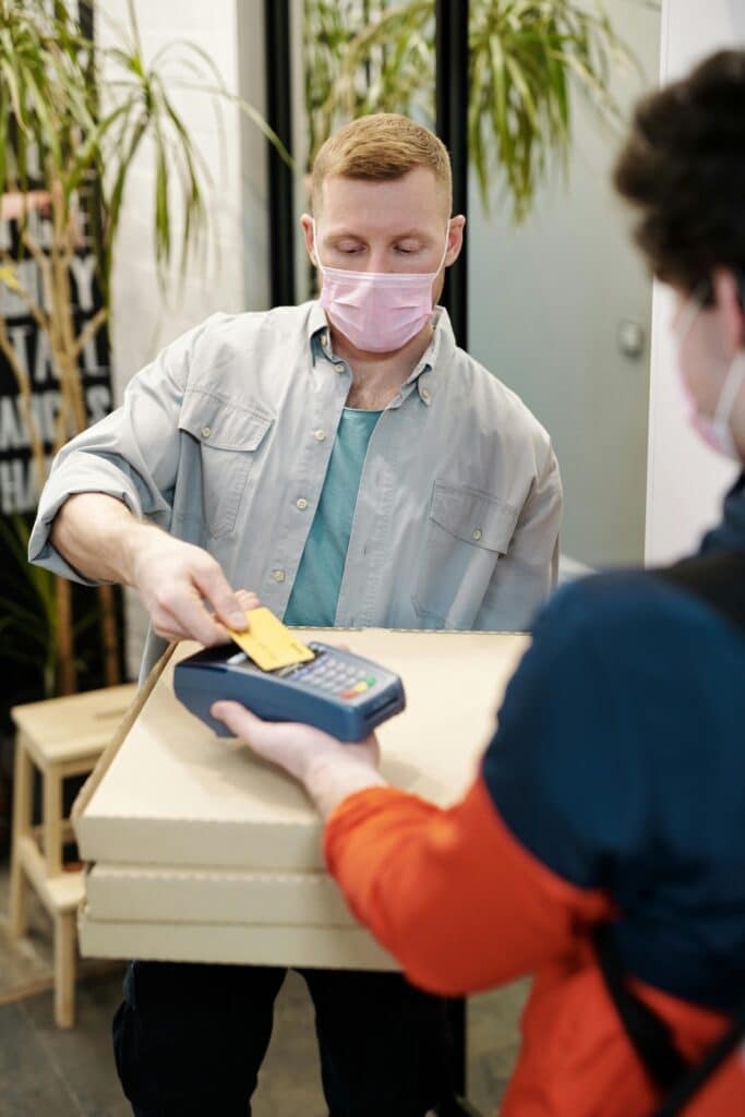 pexels-photo-4393429-4393429 Masked delivery interaction with contactless payment for safety.